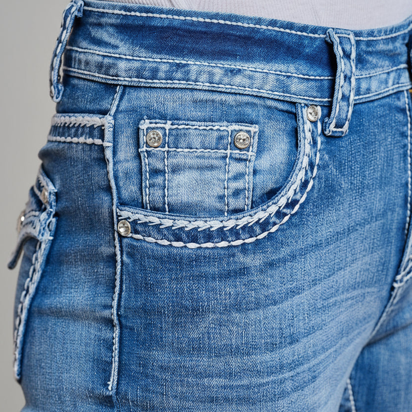 Blue denim jeans back pocket close-up with decorative stitching and metal accents