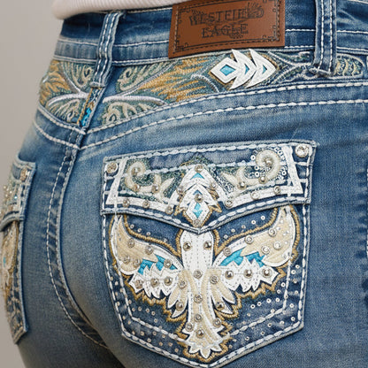 Blue denim jeans close-up of front pocket with ornate eagle embroidery and studs