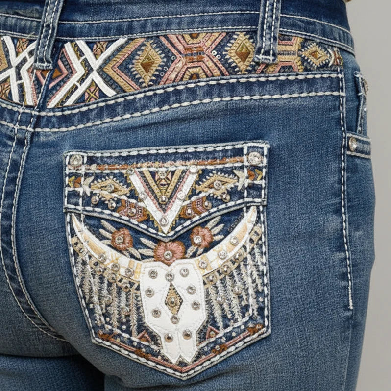 Blue jeans back pocket with embroidered graphic and studded embellishments.