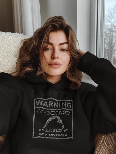 Black long sleeve shirt with warning gymnast rhinestone graphic, close-up