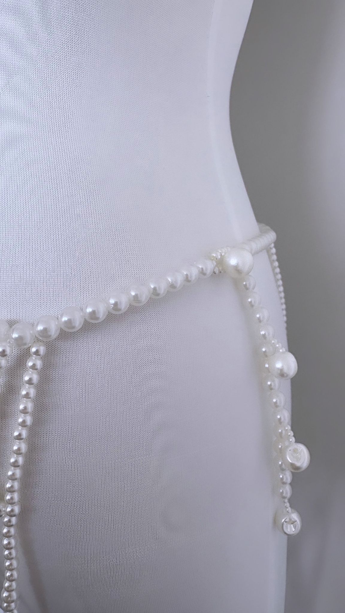Skirt hem with pearl-bead trim and looped knot details on mesh fabric