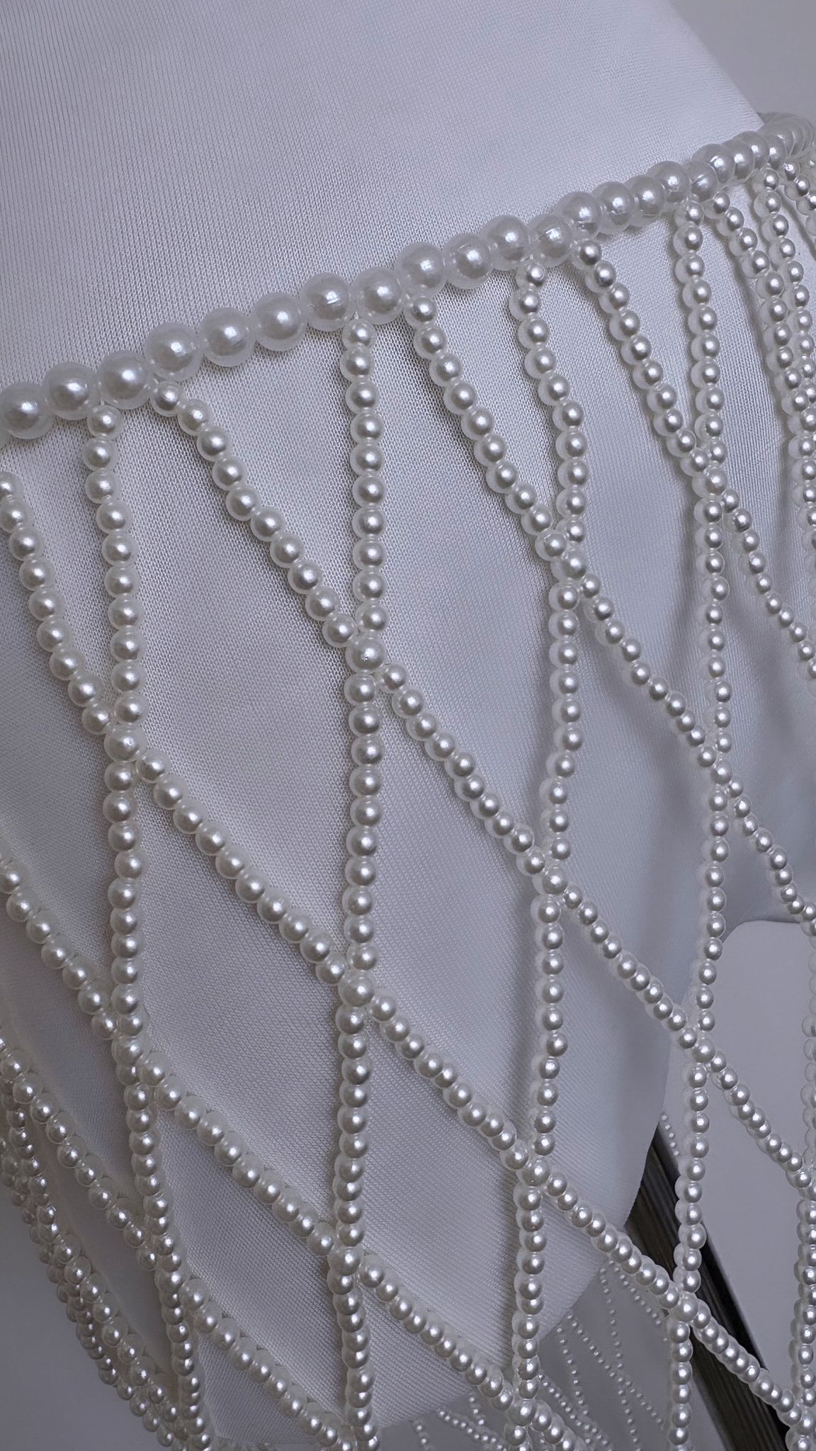 Close-up of pearl-bead rows on diamond lattice mesh skirt