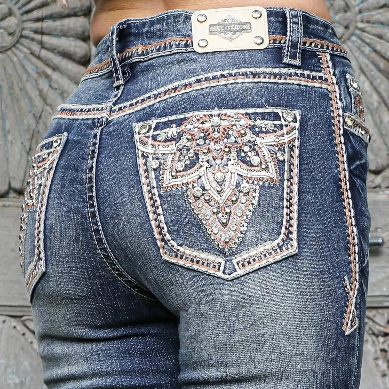 Back-pocket detail: embellished blue denim jeans with rhinestone-like motif and trim