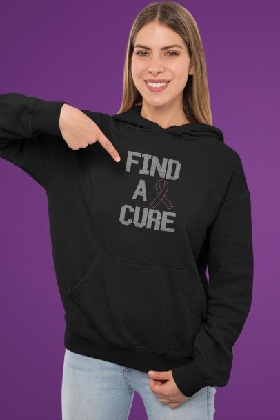 Person wearing a black hoodie with 'Find a Cure' text and a pink ribbon on a purple background