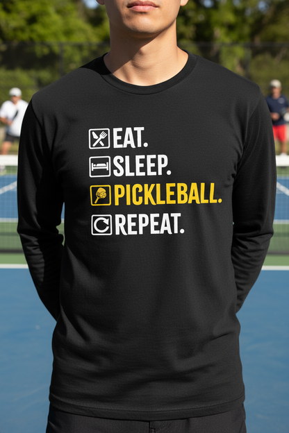 A man wearing a black long-sleeve t-shirt with a graphic print on a pickleball court. The graphic reads 'EAT.